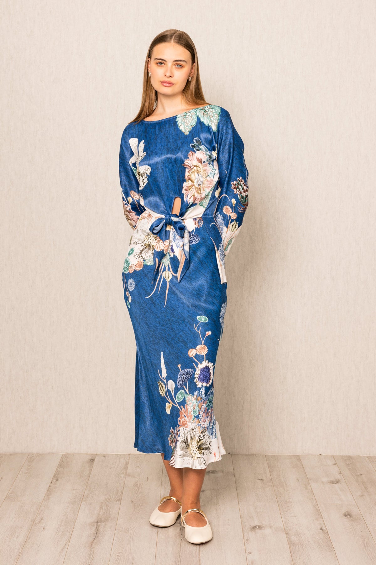 Woman wearing a blue floral dress against a plain background