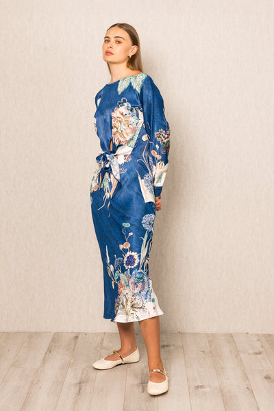 Woman wearing a blue floral kimono-style dress against a plain background
