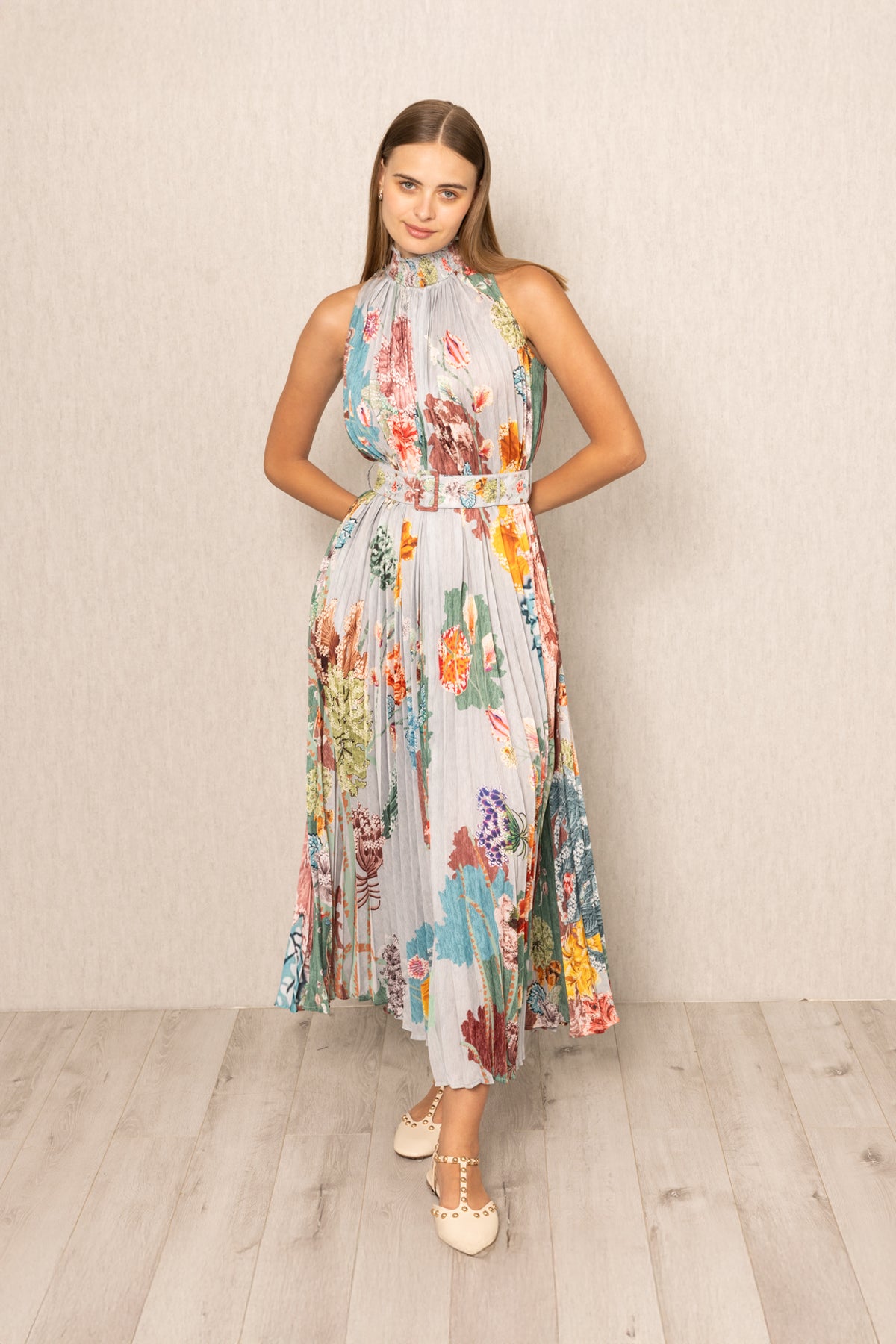 Woman wearing a floral dress in belted against a plain background