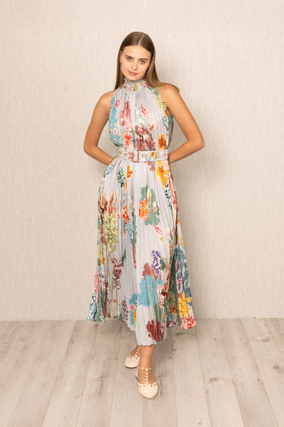 Woman wearing a floral dress in belted against a plain background