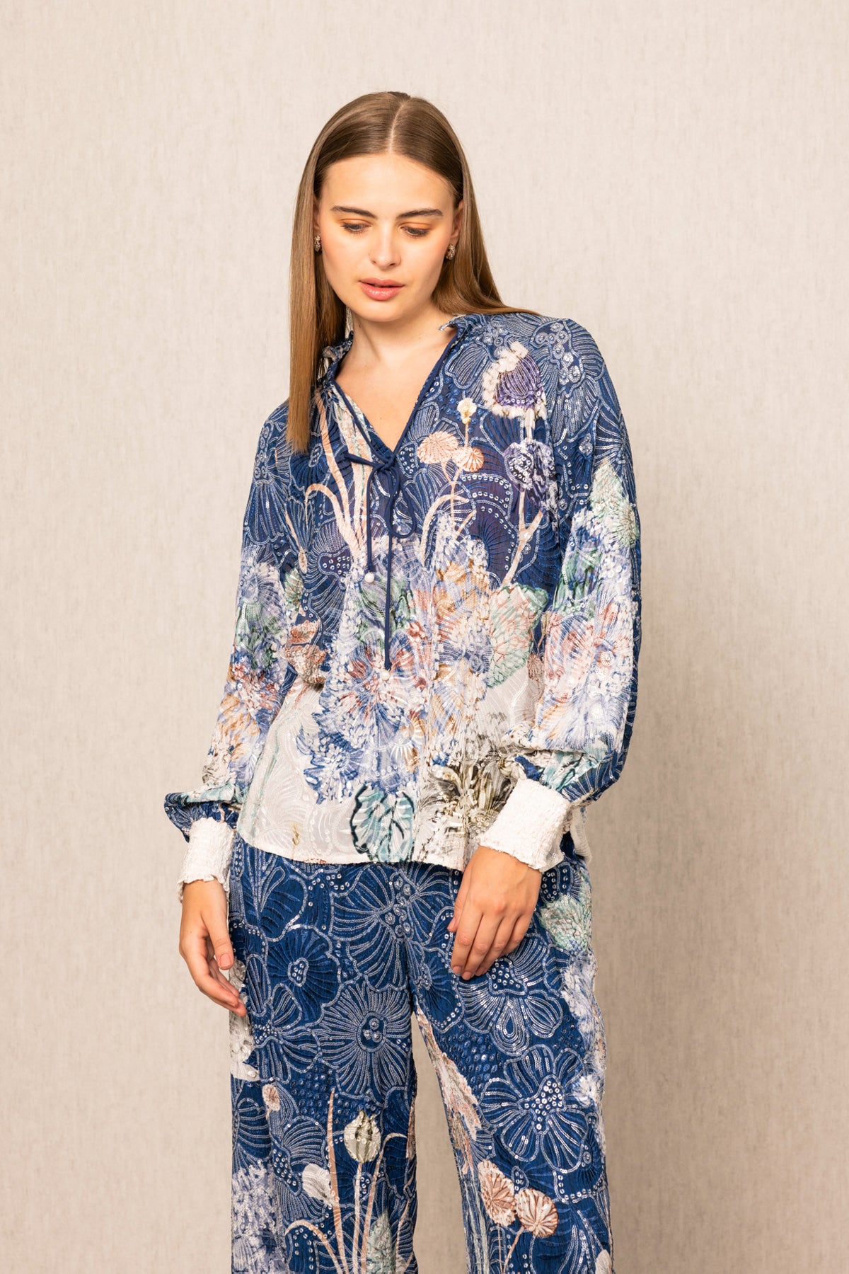 Woman wearing a blue floral outfit against a beige background