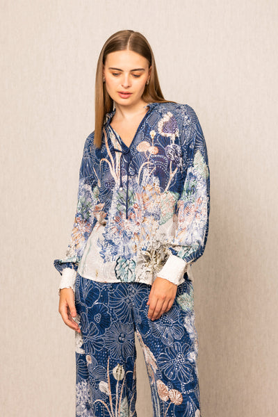 Woman wearing a blue floral outfit against a beige background