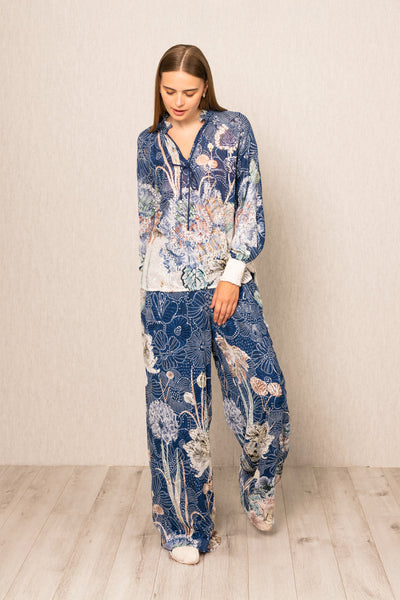 Woman wearing a blue floral pajama set against a plain background