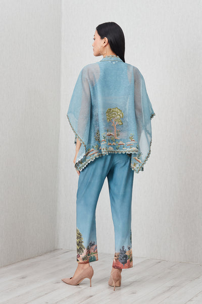 Woman wearing a light blue outfit with tree patterns in a minimalistic setting