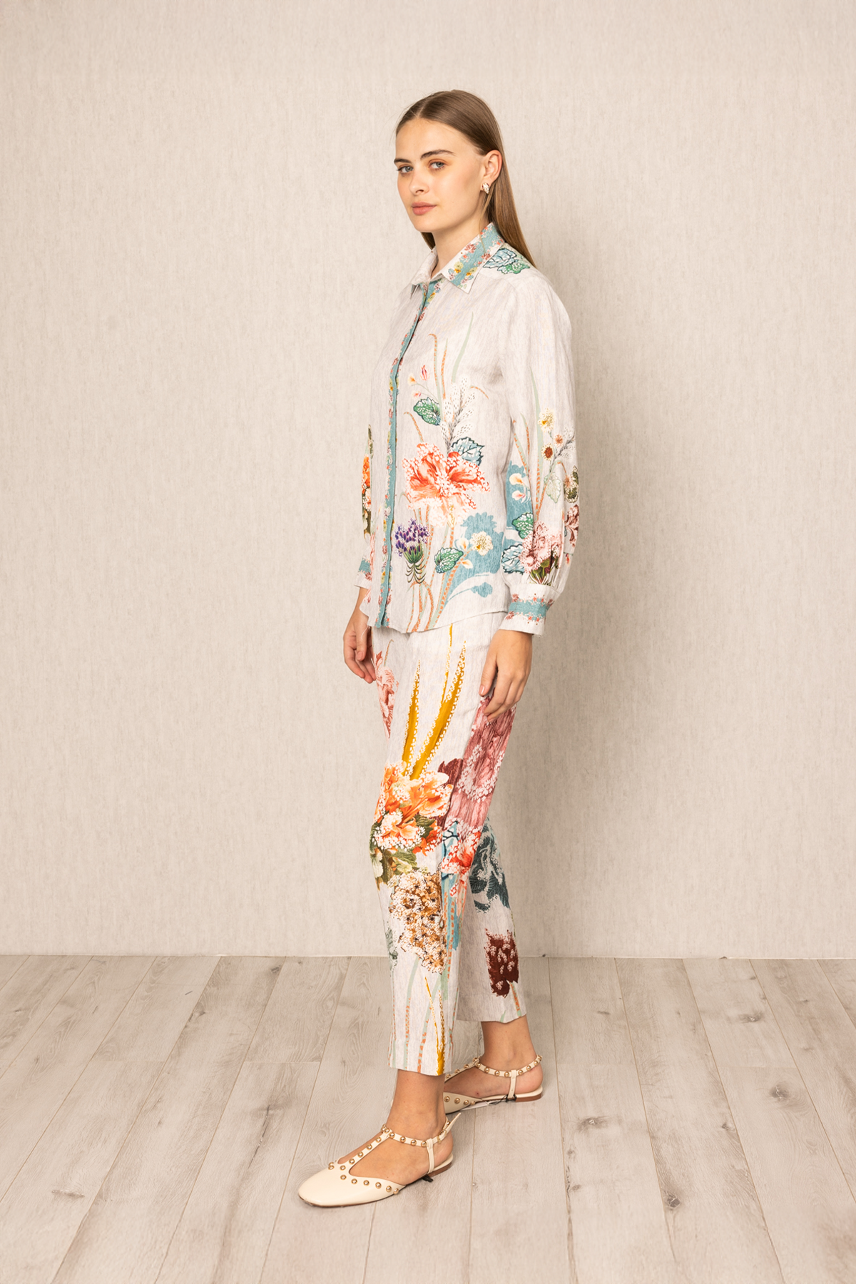 Woman wearing a floral outfit standing against a plain background